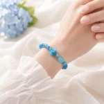 AVENSU aqua blue crystal bracelet worn on wrist with flower charm and faceted gemstone