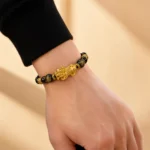 Black obsidian Pixiu abundance and protection bracelet with gold-tone charms worn on wrist