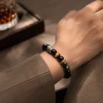 Black obsidian and tiger eye strength and protection bracelet with engraved metal accents worn on wrist