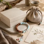 Blue gemstone and natural wood lotus bracelet displayed with a cream gift box and linen storage pouch