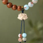 Close-up of blue gemstone and wood bracelet with carved lotus pendant and hanging bead tassels
