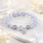 Celestial blue crystal bead bracelet with silver planet charm in a soft floral setting