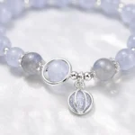 Close-up detail of celestial blue bead bracelet with silver planet charm and circular centerpiece