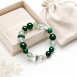 Emerald green mixed crystal bead bracelet displayed with an ivory jewelry box and drawstring pouch
