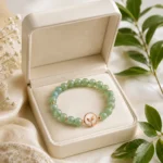 Green aventurine growth and renewal bracelet with rose gold leaf charm displayed in open cream gift box