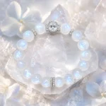 Moonstone square crystal bracelet displayed on clear quartz crystals with soft blue flowers