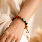 Multicolor gemstone and natural seed bead bracelet with decorative tassel worn on wrist