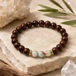 Natural dark wood and blue gemstone balance bracelet displayed on stone with clear quartz crystals