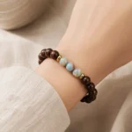 Natural dark wood and blue gemstone balance bracelet with gold-tone spacers worn on wrist