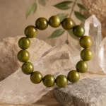 Olive green wood bead bracelet displayed with clear quartz crystals and natural stones