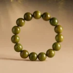 Olive green wood bead bracelet displayed in a warm natural forest-inspired setting