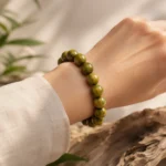 Olive green wood bead bracelet worn on wrist in a warm natural setting