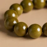 Close-up detail of polished olive green wood beads showing natural grain texture