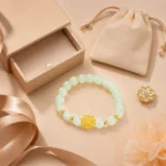 Pale green gemstone lotus bracelet displayed with peach gift box, velvet pouch and satin ribbon