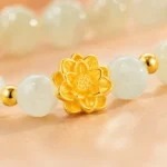 Close-up of pale green gemstone lotus bracelet with detailed gold-tone flower centerpiece
