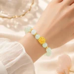 Pale green gemstone lotus bracelet with gold-tone flower centerpiece worn on wrist