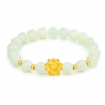 Pale green gemstone lotus bracelet with gold-tone flower centerpiece on white background