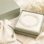 Pale green and white stone bead bracelet displayed in a sage green jewelry box with gift pouch