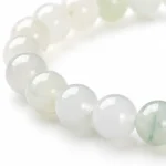 Close-up detail of pale green and white stone bracelet beads with translucent polished texture