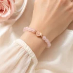 Rose quartz love and self-acceptance bracelet with heart lotus charm worn on wrist