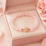 Rose quartz love and self-acceptance bracelet with heart lotus charm displayed in open pink gift box