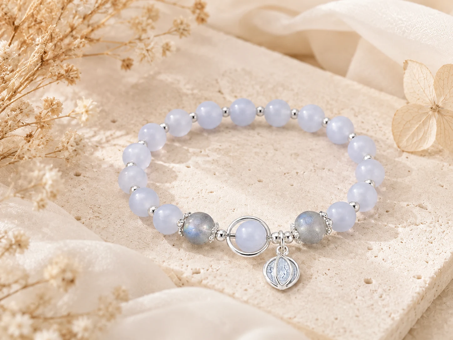 Blue chalcedony bracelet with pale blue beads, labradorite accents, silver circle centerpiece, leaf charm, dried flowers, and AVENSU calm styling