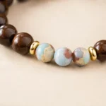 Close-up of brown wood bead bracelet with three blue patterned gemstone beads and gold spacer accents