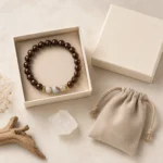 Brown wood and blue gemstone bracelet displayed in a cream gift box with jewelry pouch