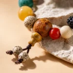 Close-up of multicolor feng shui bead bracelet with carved wooden bead, red accent bead and tassel detail