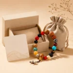Multicolor feng shui bead bracelet displayed with an open gift box, jewelry pouch and illustrated card