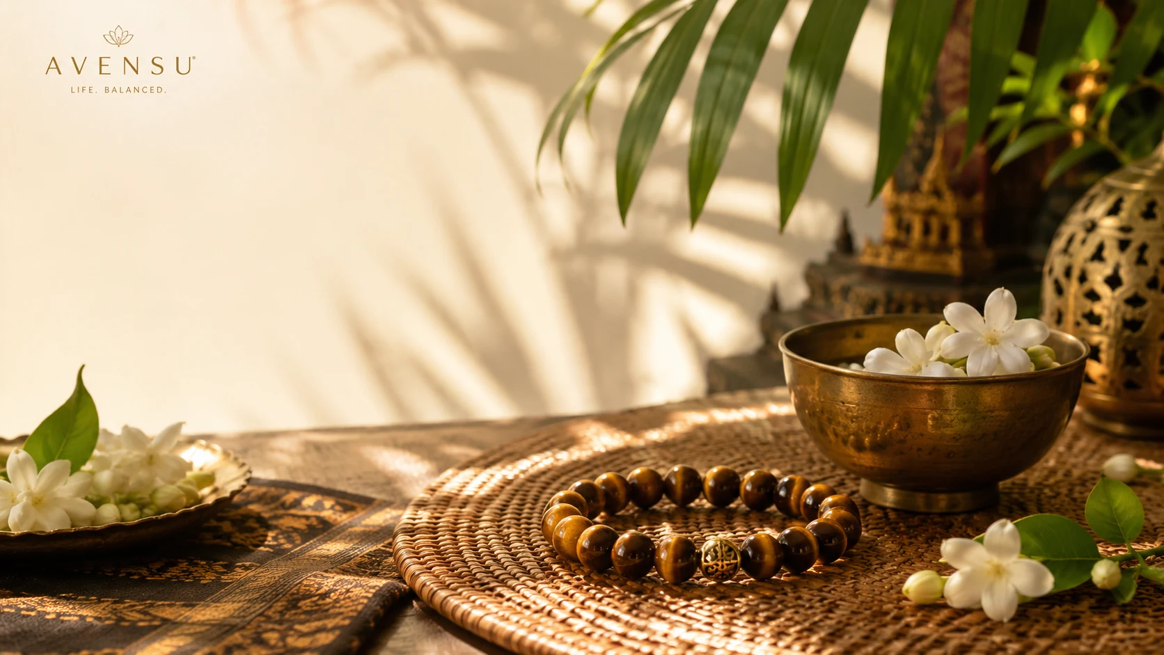 Tiger eye life balance bracelet with jasmine flowers, golden bowl, tropical leaves, woven tray, and warm AVENSU ritual styling