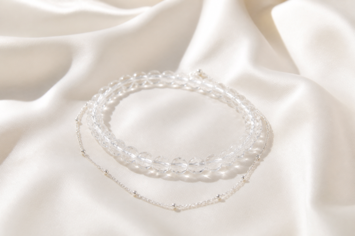 Clear quartz bead bracelet layered with a silver chain on ivory silk