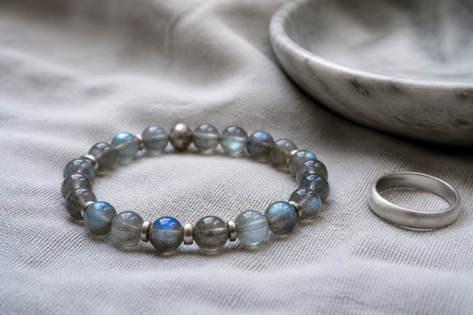 Labradorite bead bracelet on pearl grey linen beside a silver ring