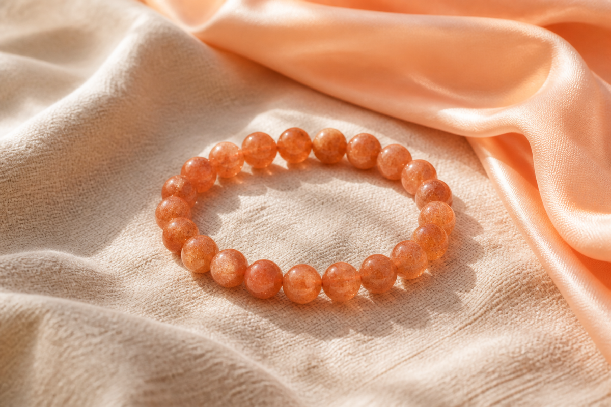 Warm orange sunstone bead bracelet on cream linen with a peach scarf