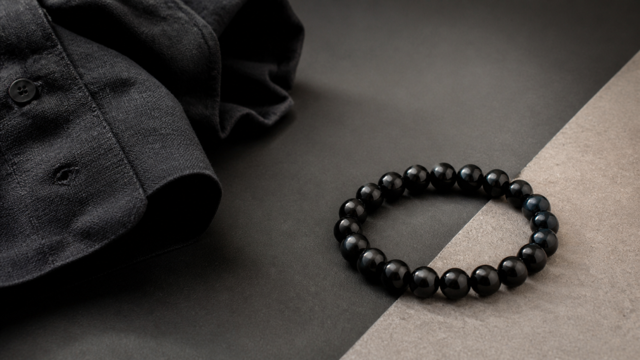 Polished black bead bracelet on a dark linen and stone tabletop