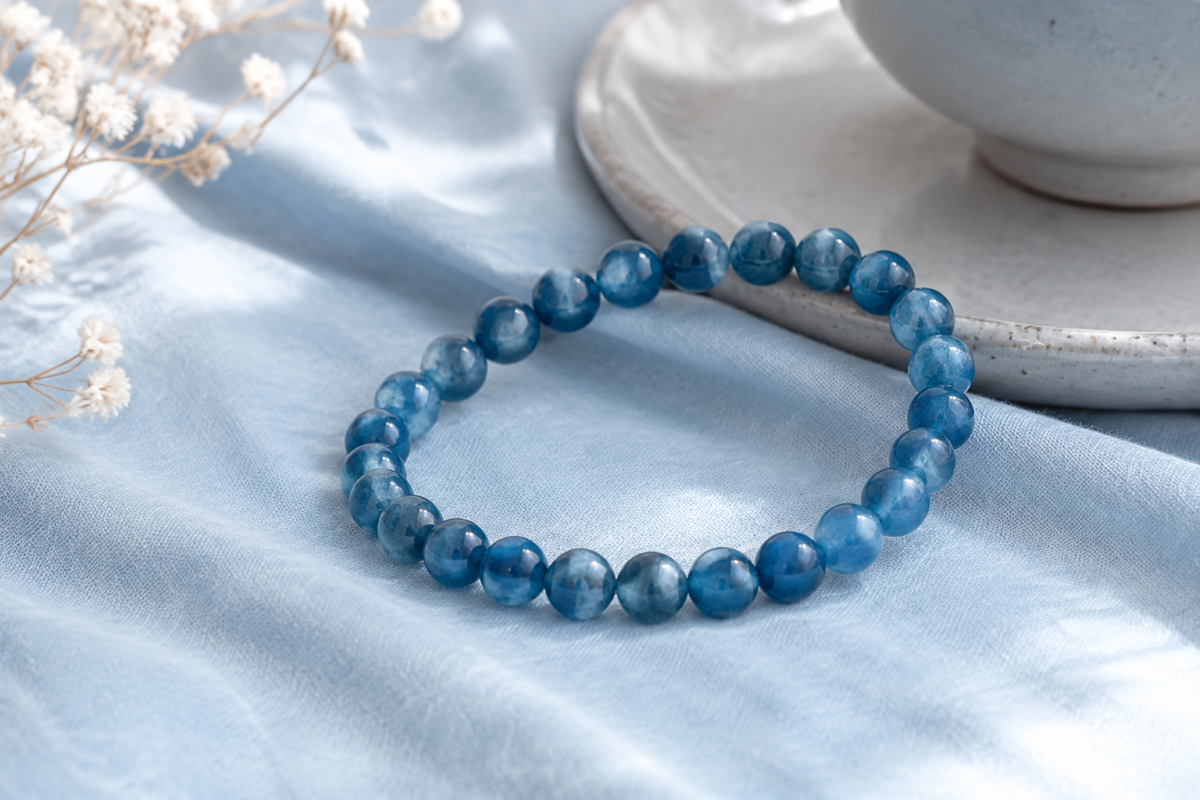 Blue apatite bead bracelet on powder blue cotton beside pale grey ceramic