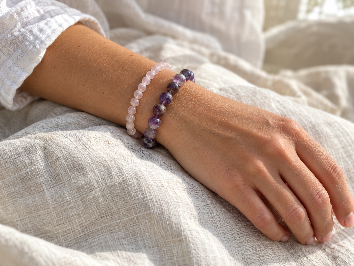 Two stacked crystal bracelets with different bead sizes worn on one wrist